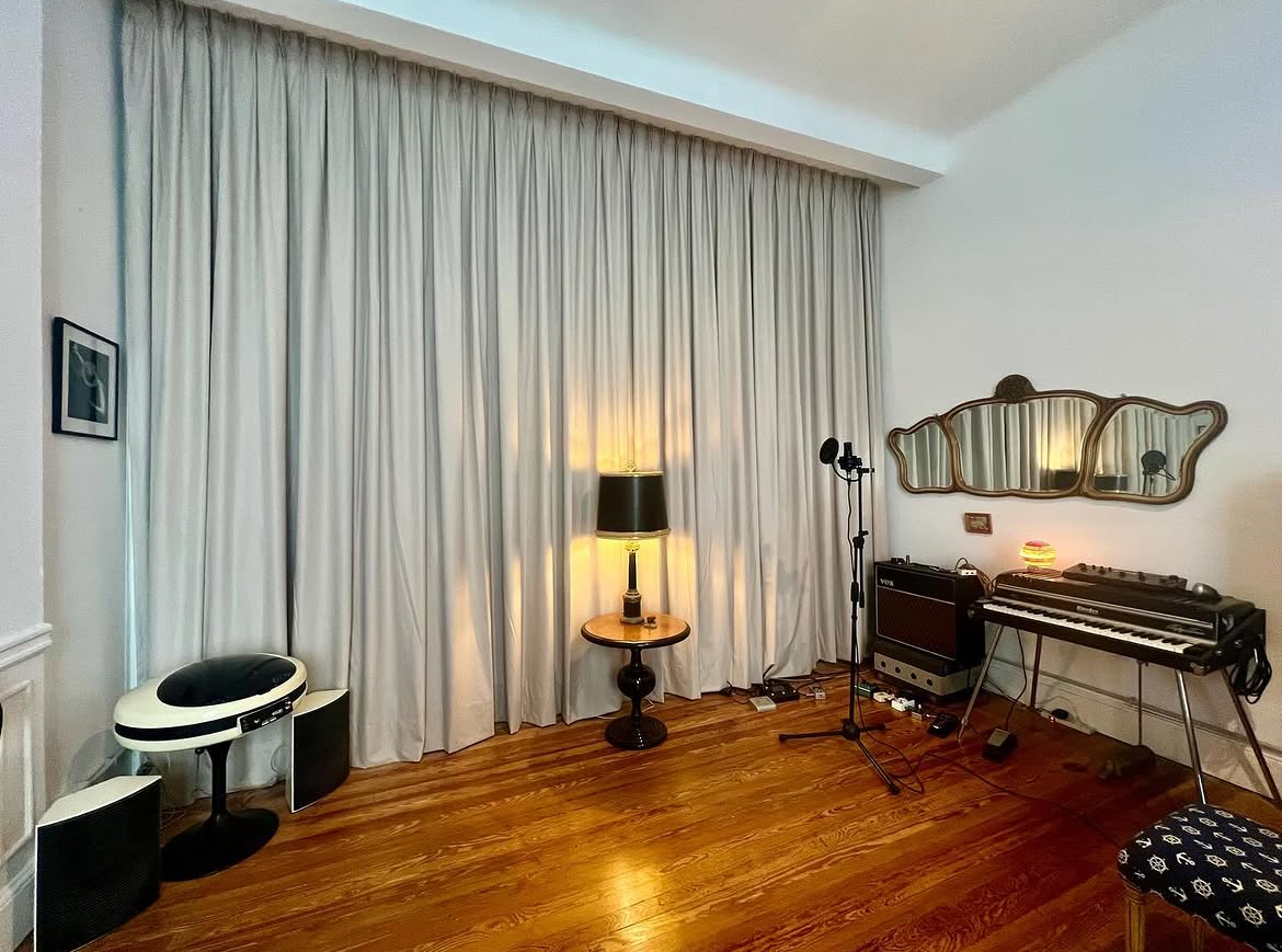 A piano standing against the studio wall beside a window